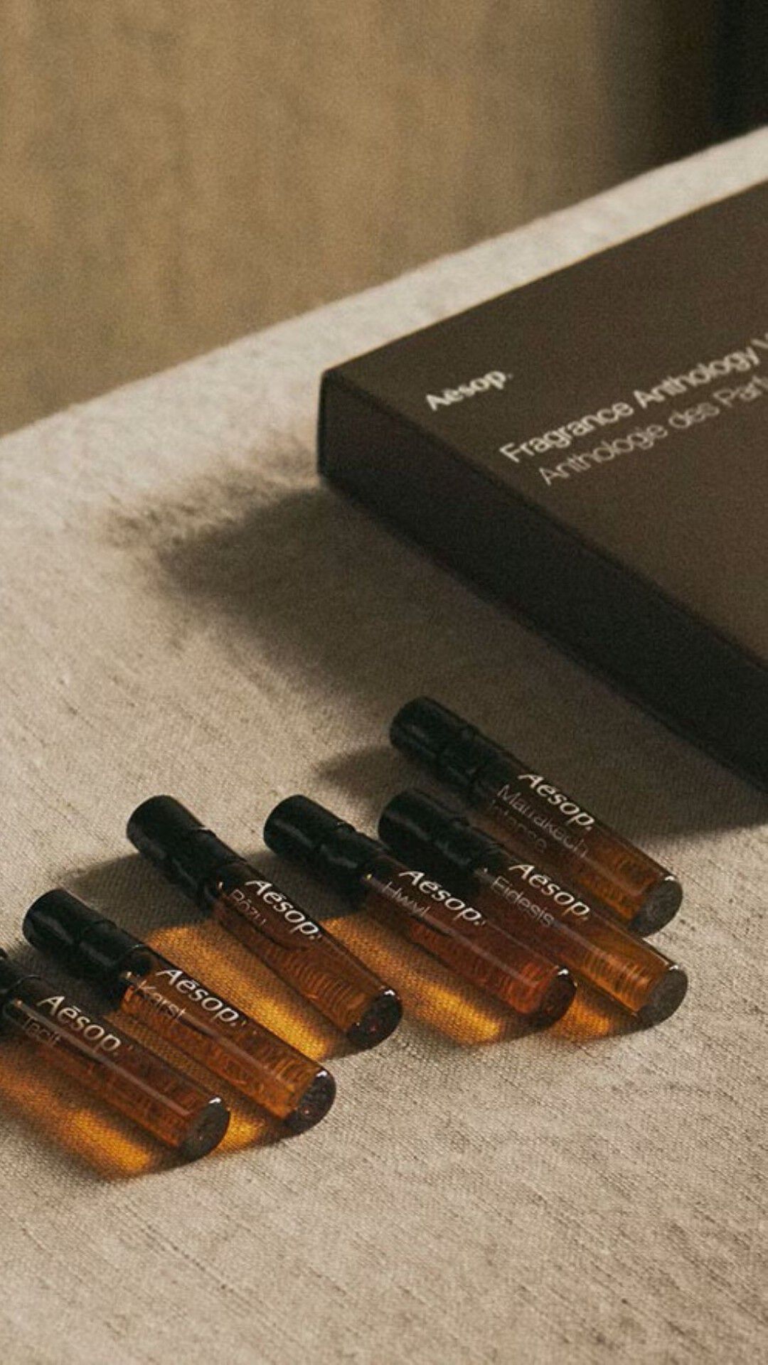 Open wooden cabinet filled with Aesop bottles in warm light.