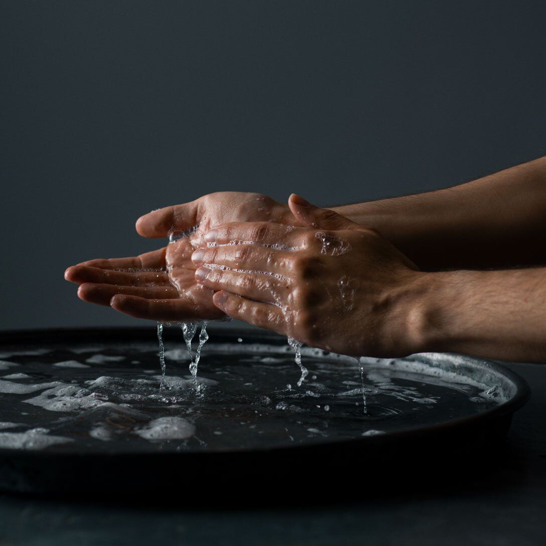 Hands rinsing with water above a dark basin.