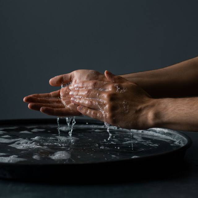 Hands rinsing with water above a dark basin.