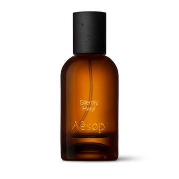 Amber glass Aesop Silently Hwyl Eau de Parfum bottle with black cap on a white background.