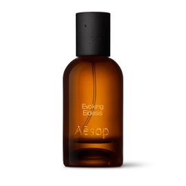 Amber glass Aesop Evoking Eidesis Eau de Parfum bottle with black cap on a white background.